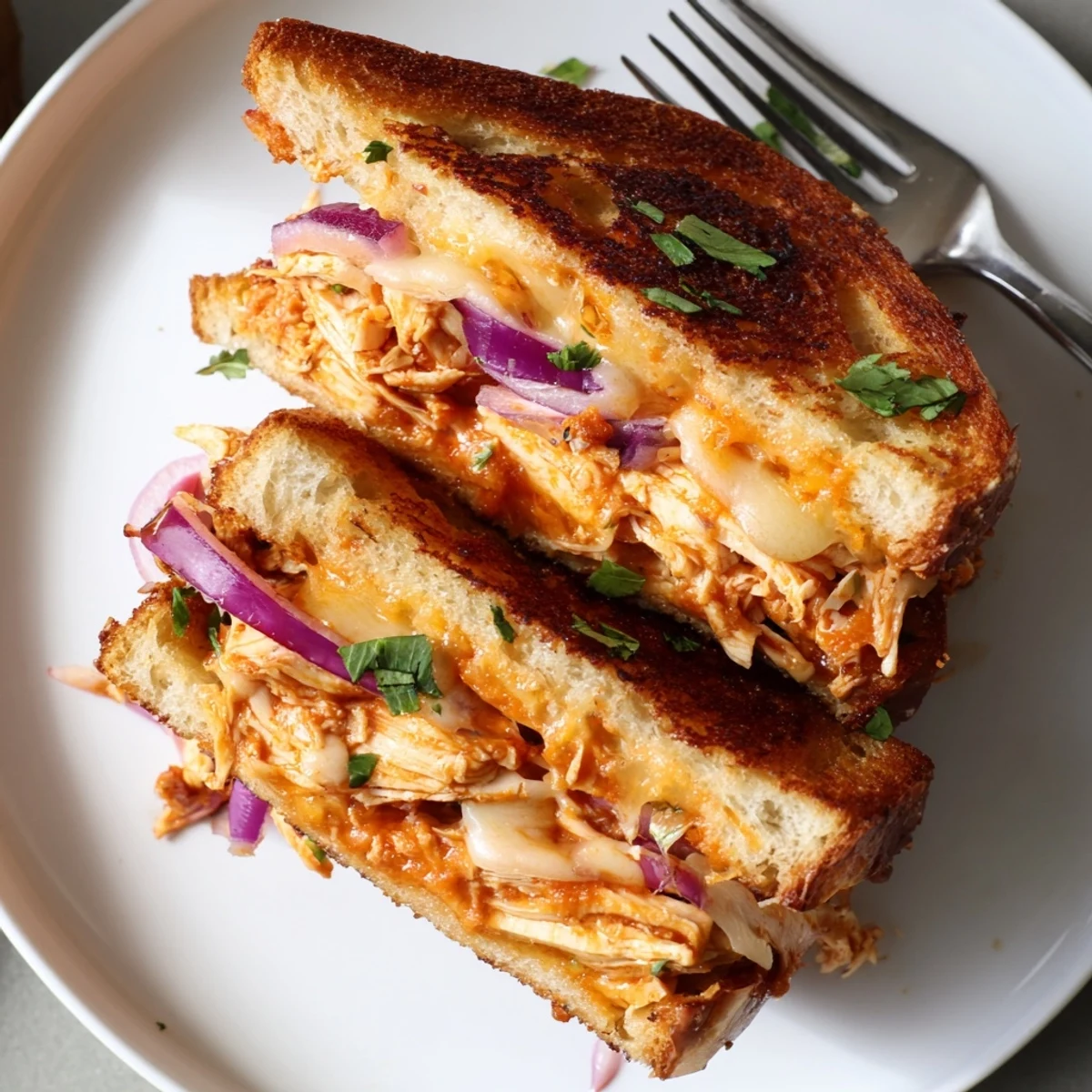 BBQ chicken grilled cheese sandwich cut diagonally displaying layers of melted cheese and smoky pulled chicken
