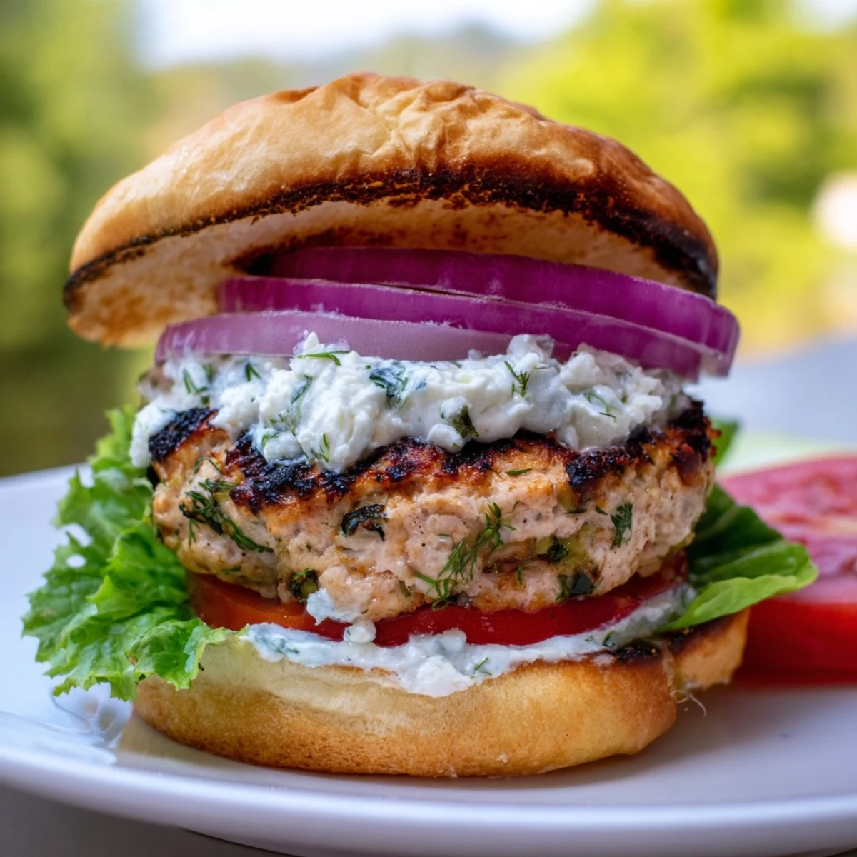 Succulent Mediterranean-style chicken patties seasoned with herbs and feta, generously topped with tangy tzatziki sauce