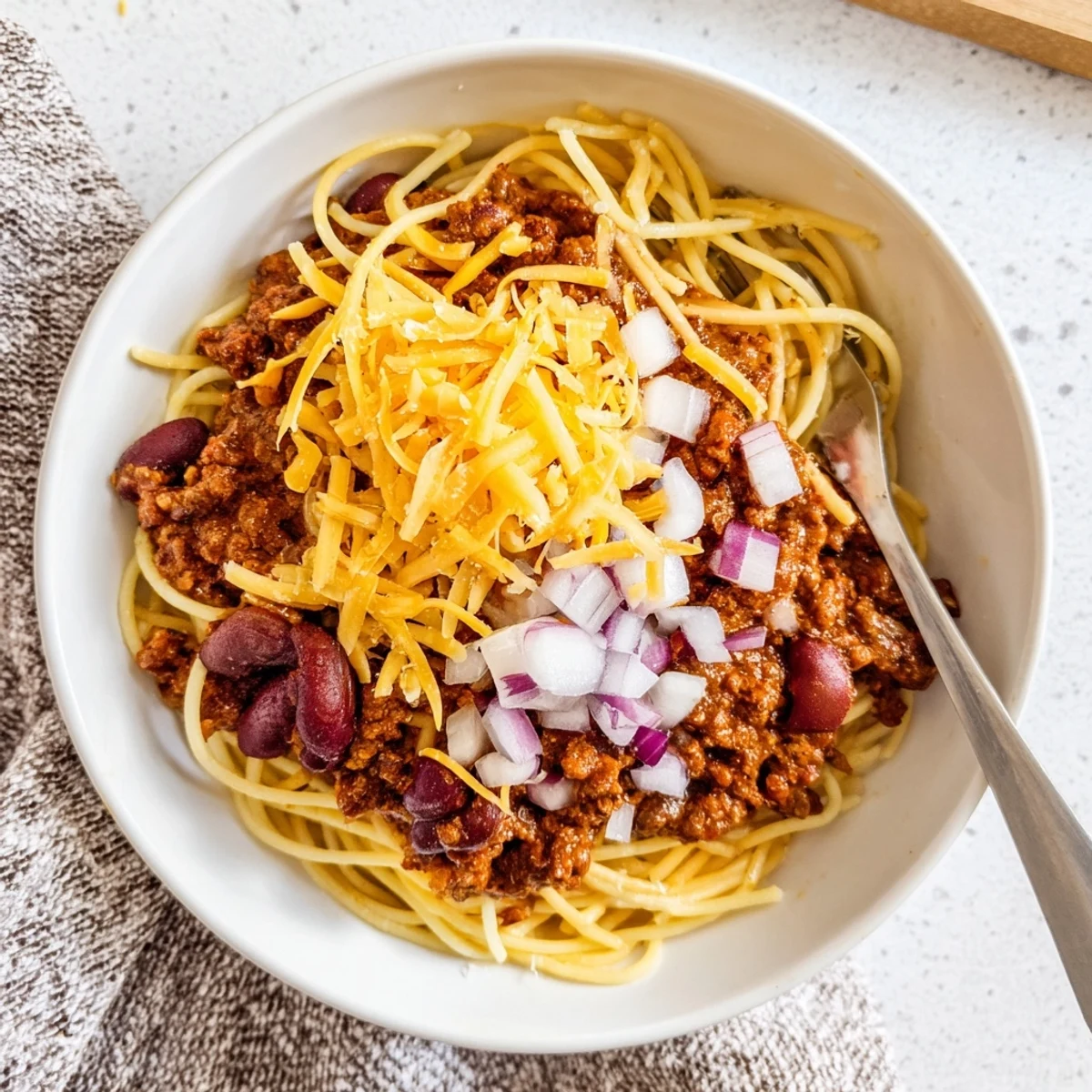 Rich Cincinnati Chili meat sauce ladled generously over pasta with shredded cheese and kidney beans