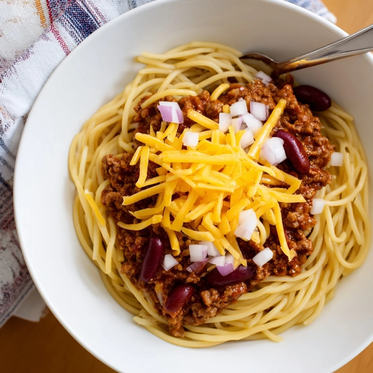 Bowl of authentic Cincinnati Chili featuring spiced beef sauce over spaghetti with golden cheese topping