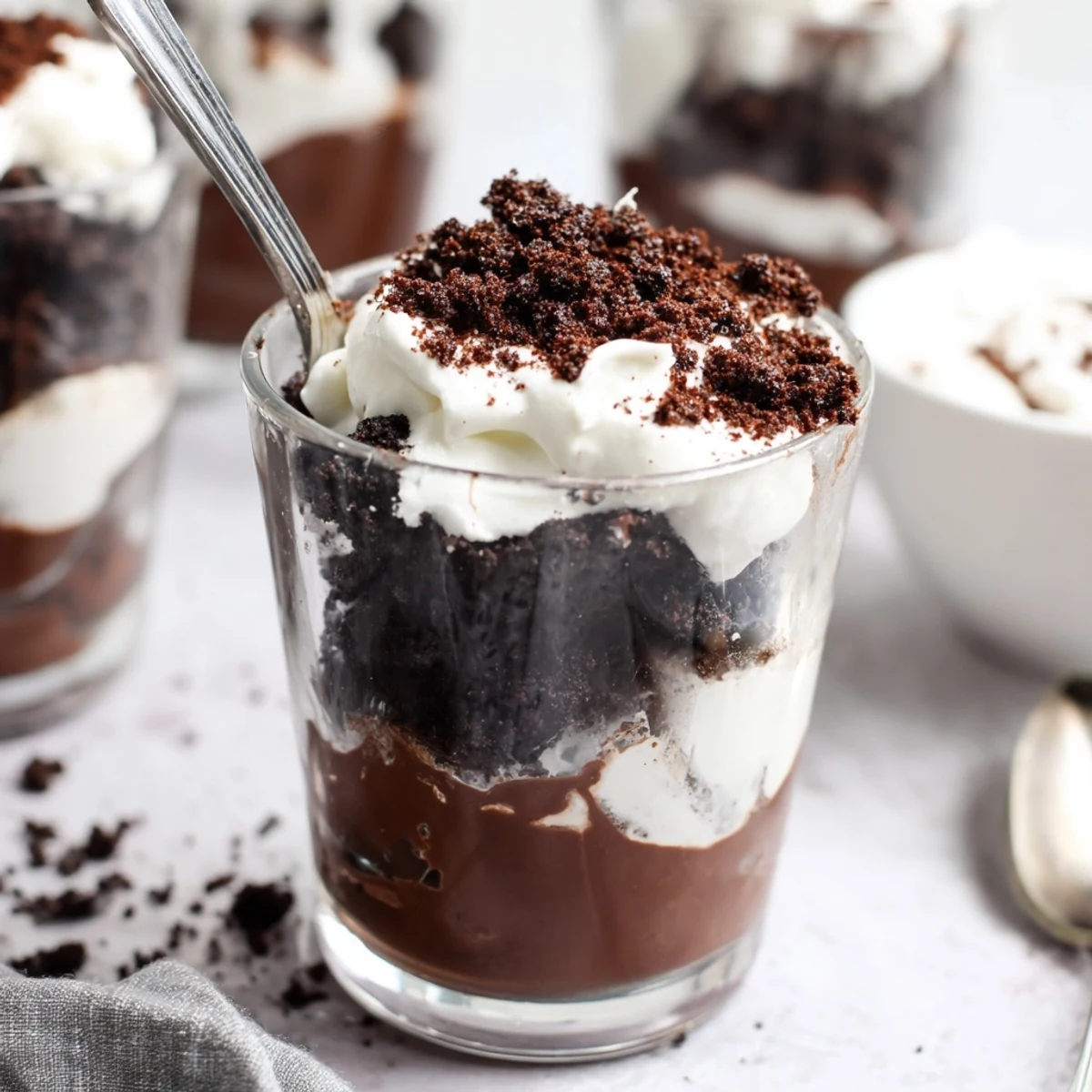 Individual serving jars of keto dirt cake topped with crunchy chocolate almond crumbs resembling dirt with layered chocolate pudding and cream