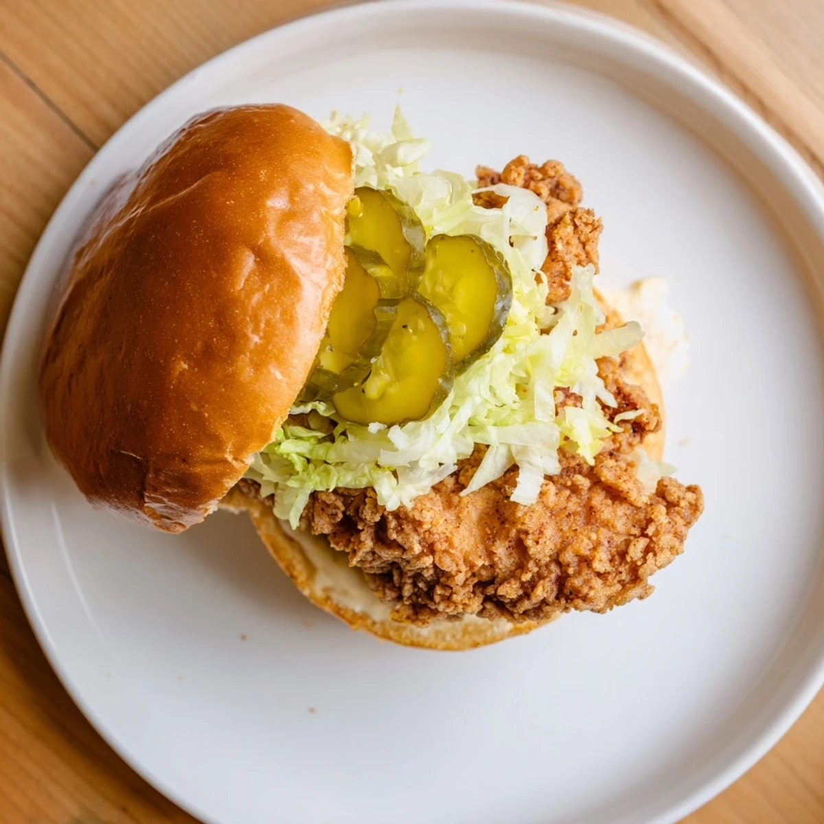 Golden pickle brined fried chicken sandwich stacked with crisp lettuce and tangy pickle slices on a toasted brioche bun