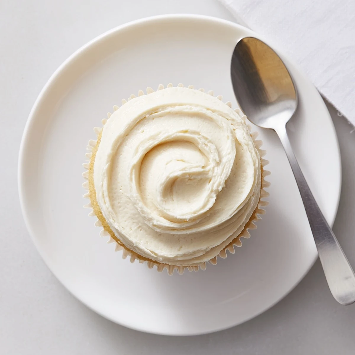 Golden vanilla cupcakes topped with fluffy buttercream frosting on a rustic white platter