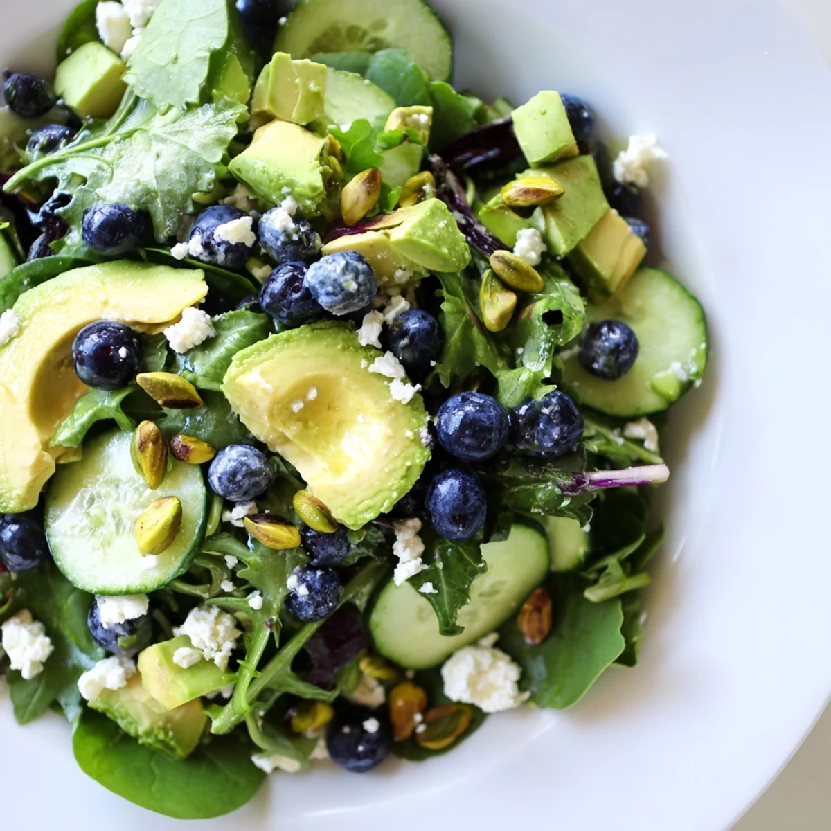 Colorful Blueberry Pistachio Spring Salad topped with creamy avocado and tangy feta cheese