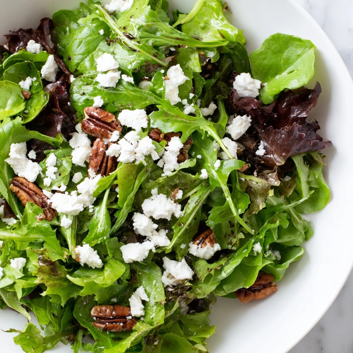Colorful spring mix salad in a wooden bowl drizzled with honey mustard vinaigrette.