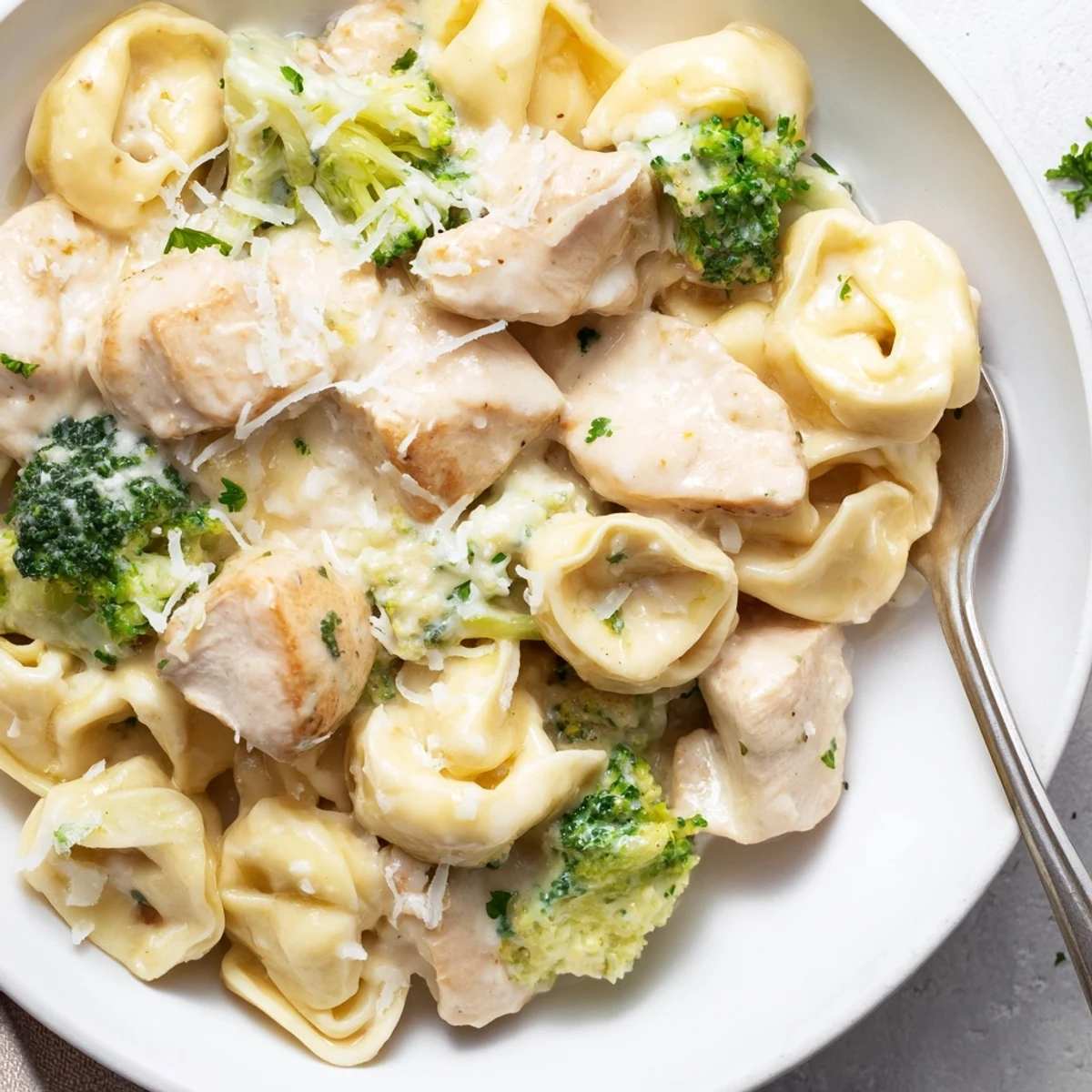 Steaming bowl of Creamy Garlic Parmesan Tortellini Chicken Broccoli Recipe, golden chicken