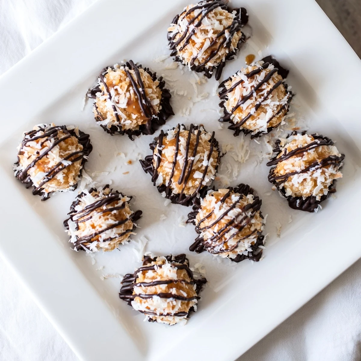 No bake Samoa bites topped with toasted coconut and drizzled dark chocolate on parchment
