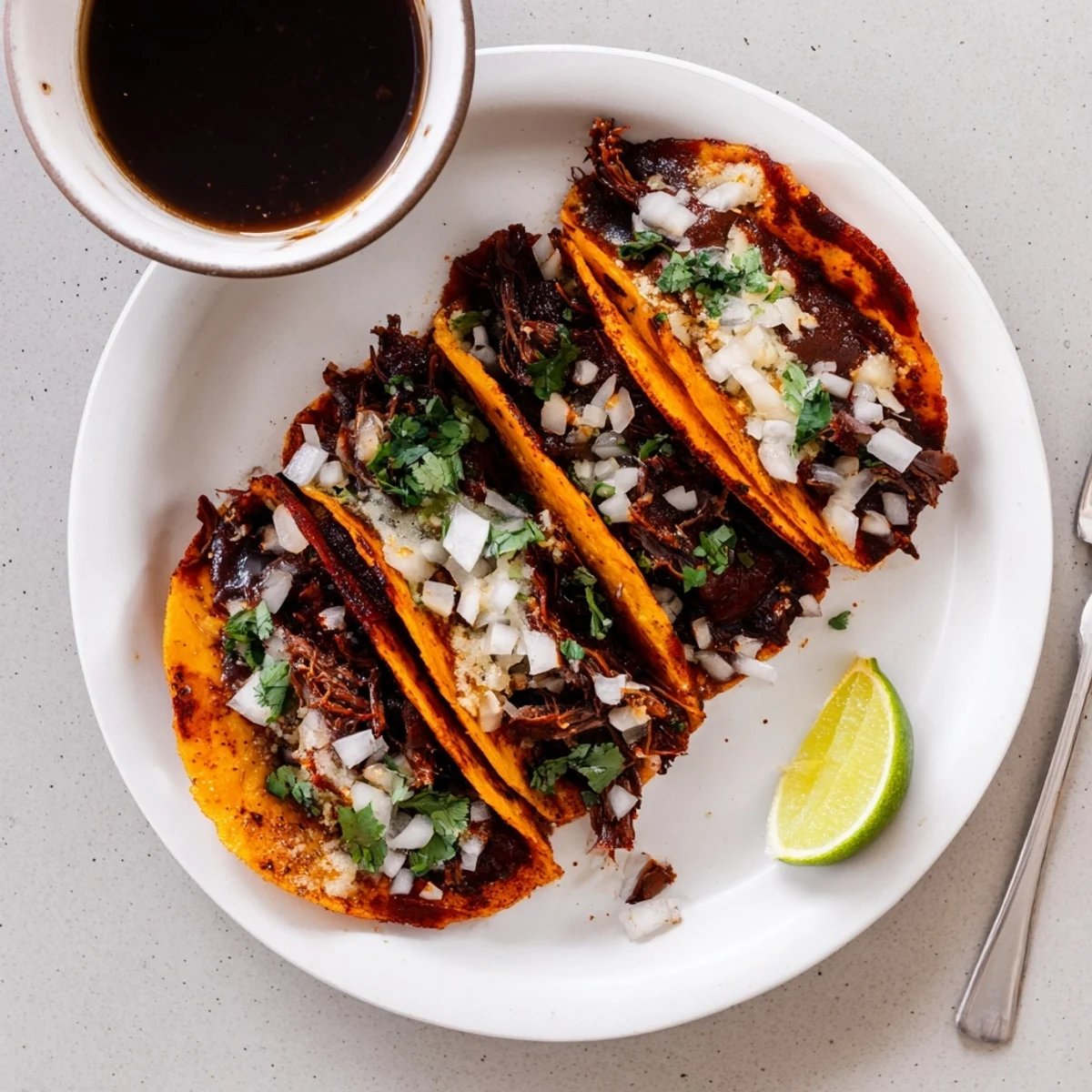 Birria tacos with juicy slow-cooked beef spilling from cheesy corn tortillas, served in a vibrant Mexican street food style spread
