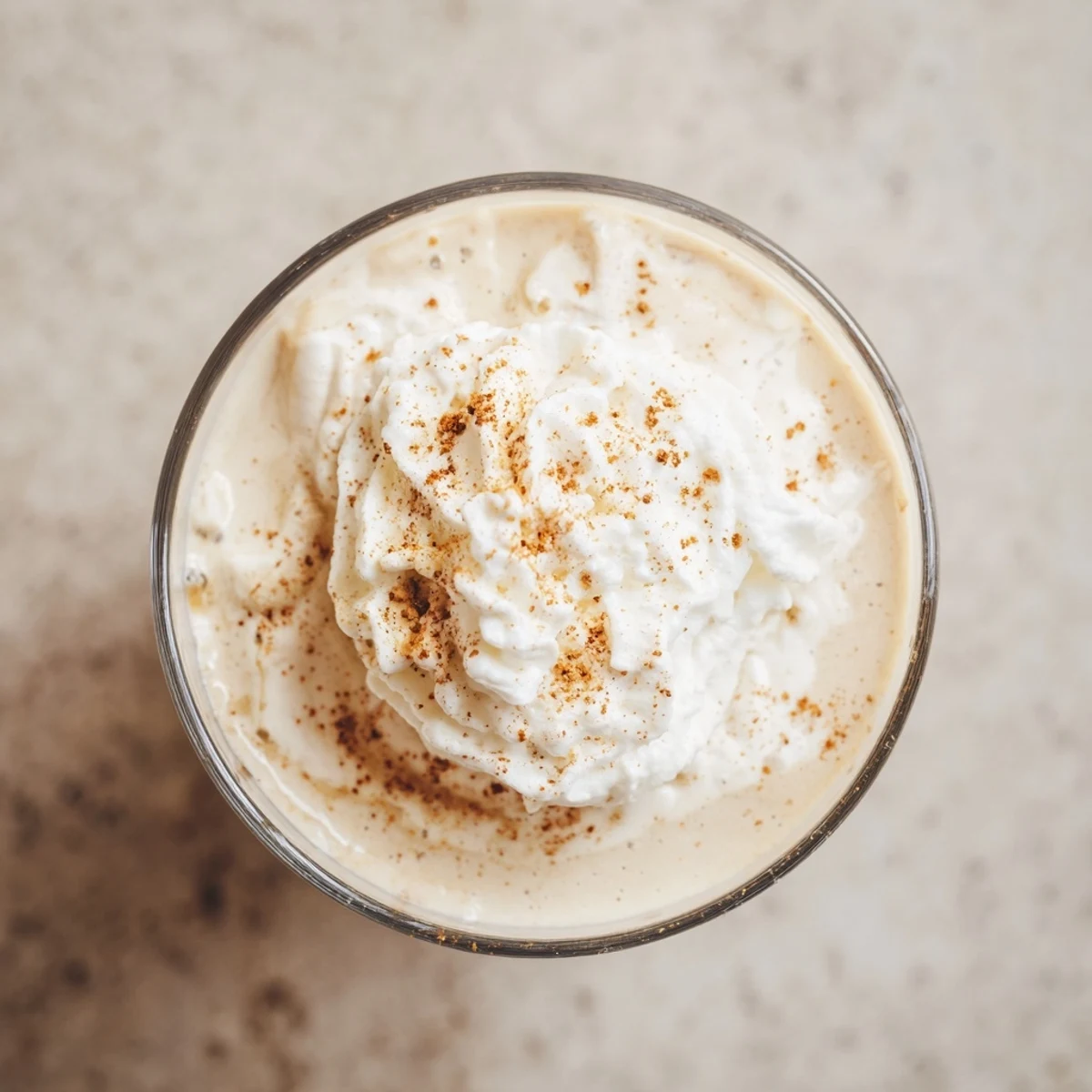Glass of creamy keto eggnog topped with whipped cream and dusted with ground nutmeg