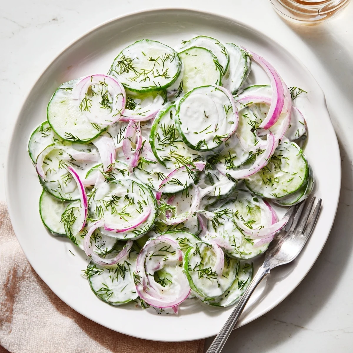 Fresh cucumber dill salad with thinly sliced cucumbers and red onion in creamy dressing