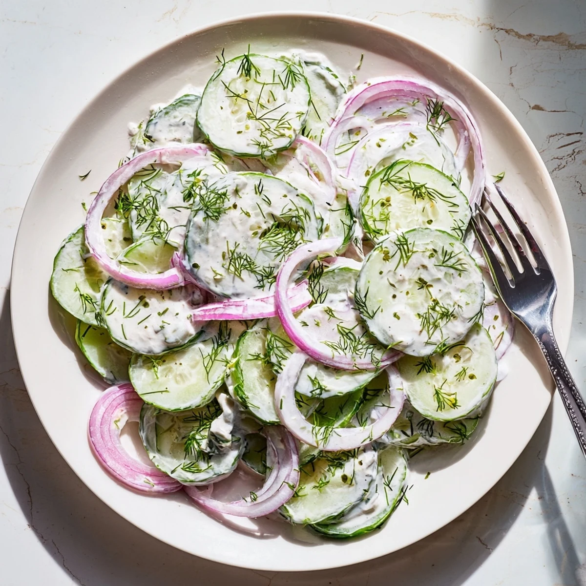Creamy cucumber dill salad featuring tangy sour cream dressing and vibrant green herbs