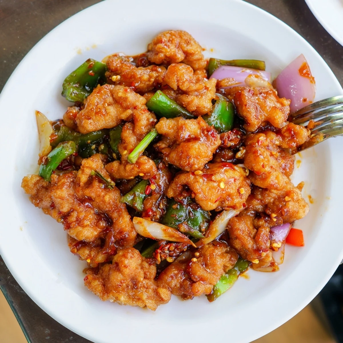 Steaming plate of Flavorful Chilli Chicken Indo Chinese, crispy, spicy, garnished spring onions