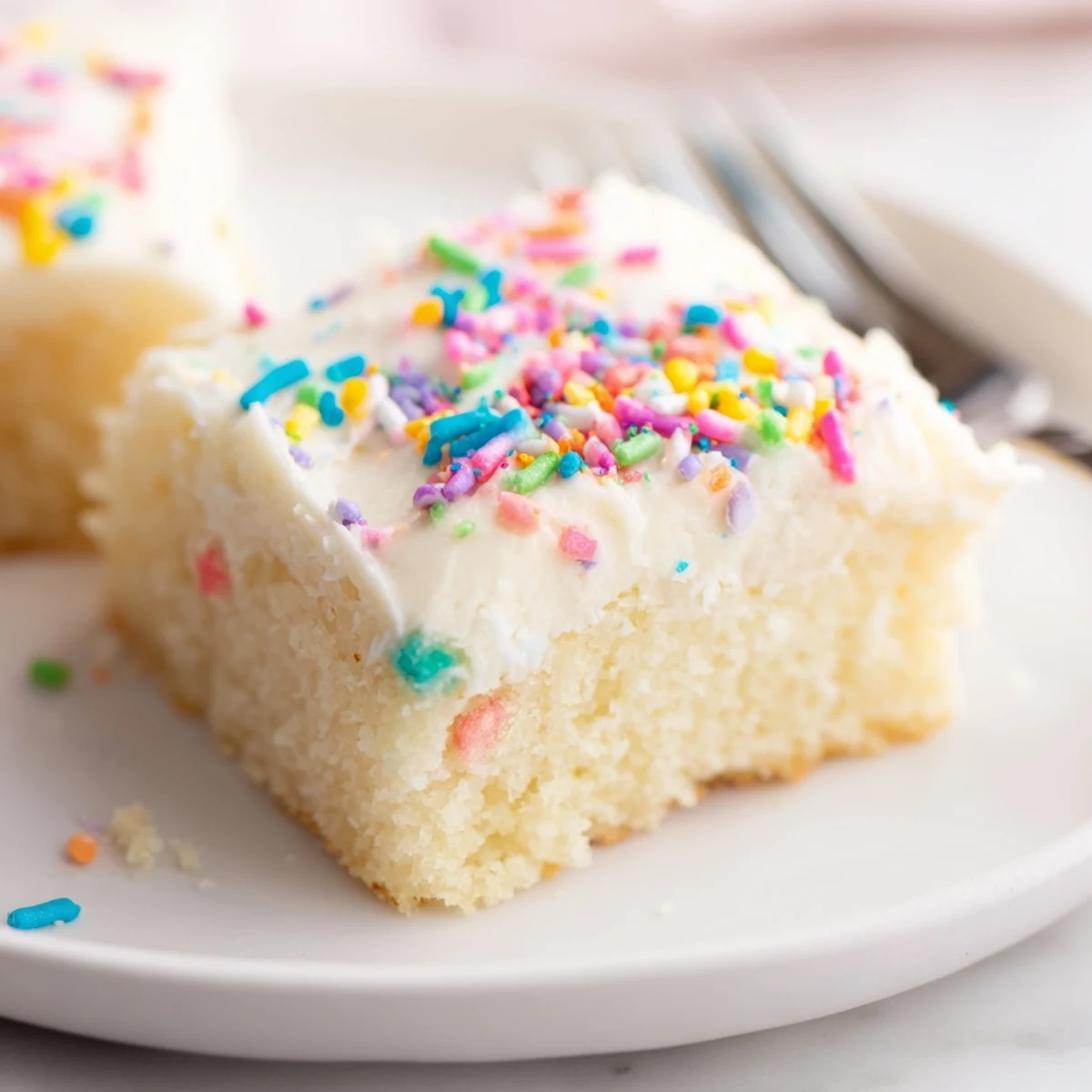 Frosted Sugar Cookie Bars glistening with creamy vanilla frosting and colorful sprinkles