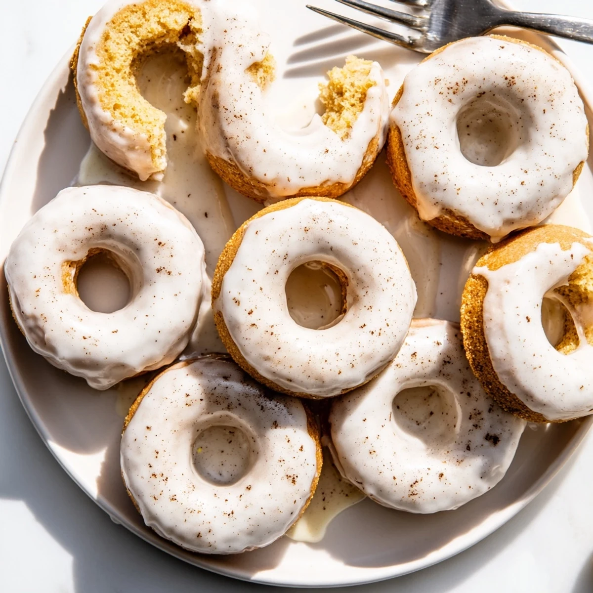 Golden banana bread donuts topped with sweet white glaze on a wire cooling rack