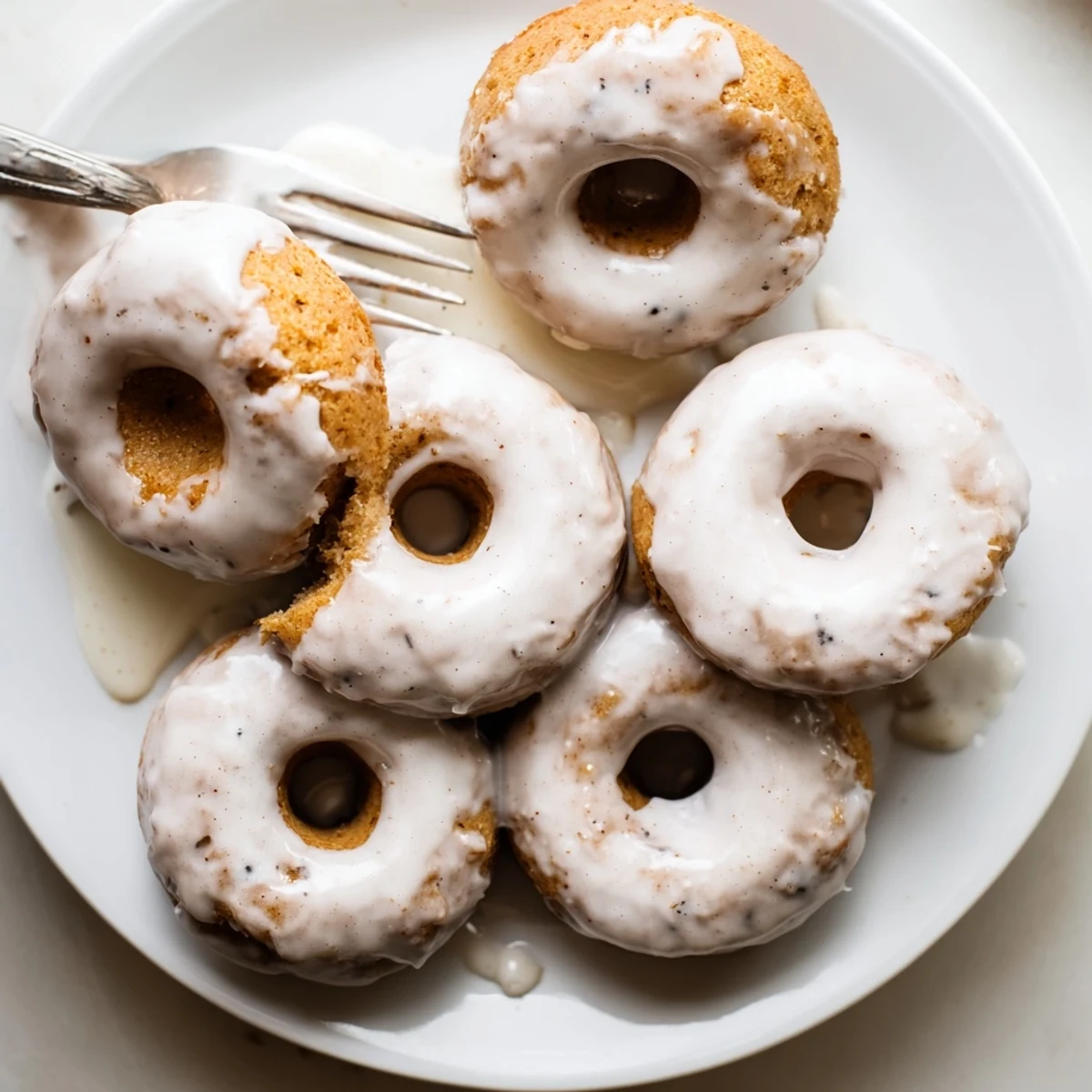 Freshly baked banana bread donuts with cinnamon swirl cooling on a white plate