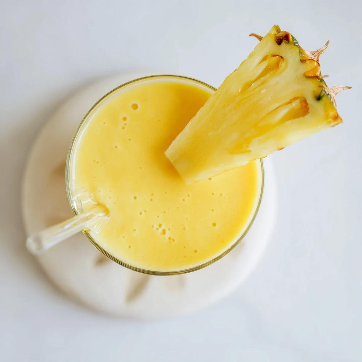 Golden tropical pineapple mango smoothie recipe served in a clear glass with fresh fruit garnish