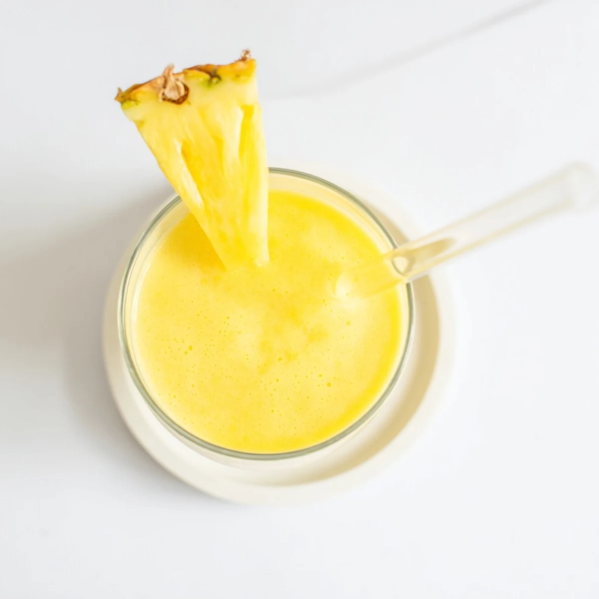 Vibrant yellow pineapple mango smoothie recipe with coconut milk displayed on a wooden kitchen counter