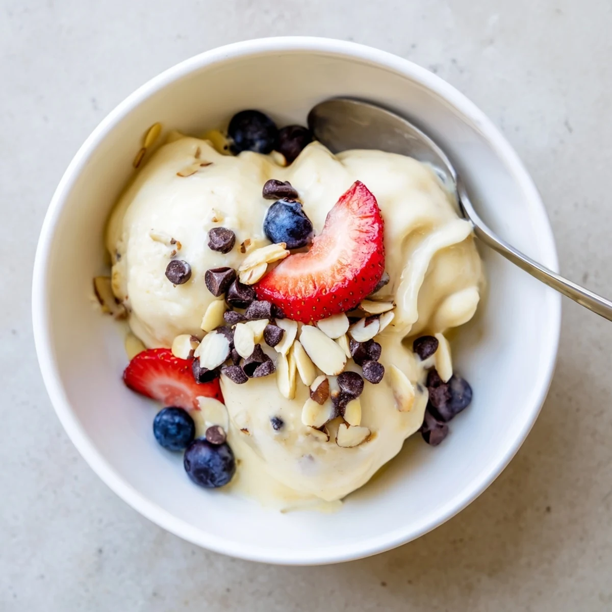Velvety dairy-free banana nice cream served in a chilled dessert bowl with crunchy nut butter and toasted coconut flakes