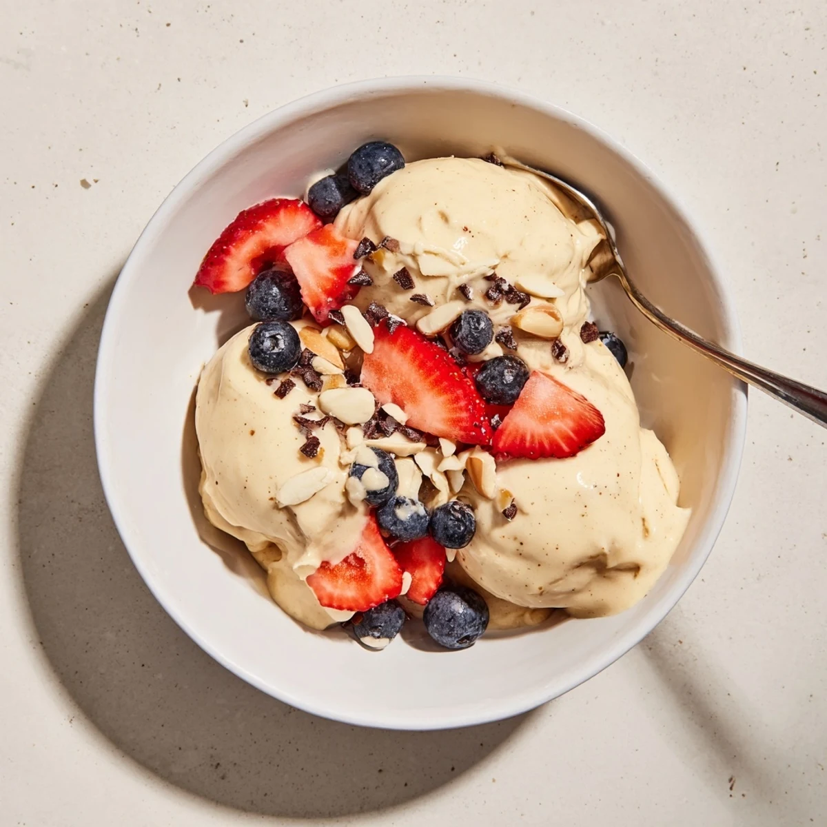 Creamy banana nice cream swirled in a glass bowl topped with fresh berries and dark chocolate chips
