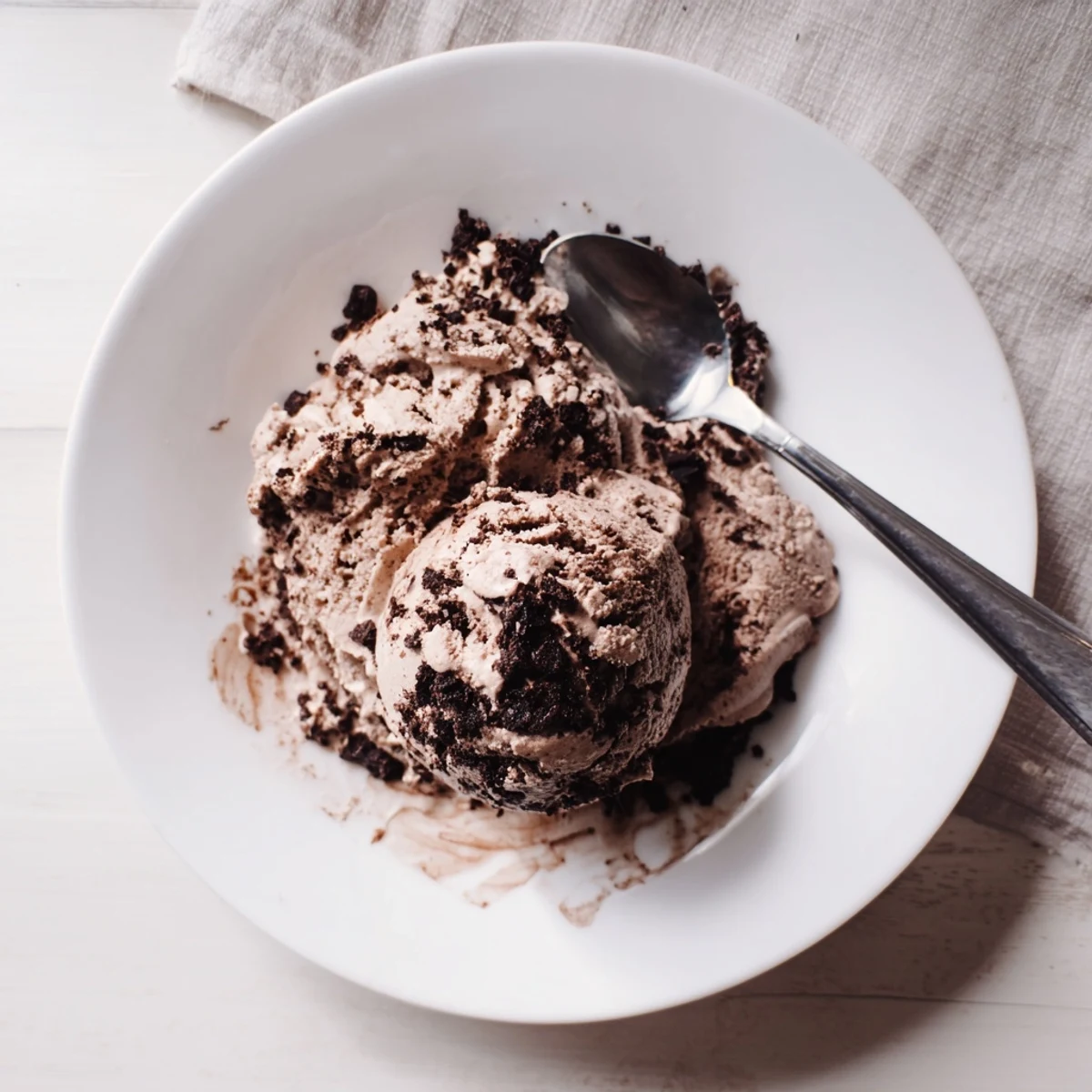 Rich chocolate sourdough ice cream swirling in a vintage glass dish with fresh raspberries