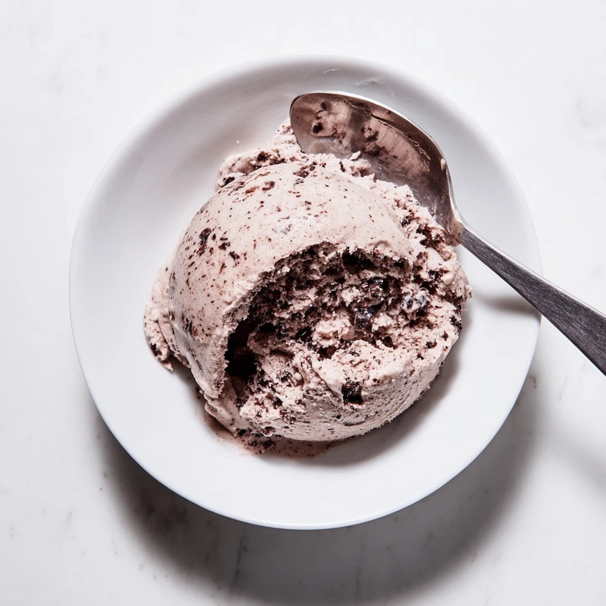 Glossy chocolate sourdough ice cream served in a chilled bowl with sea salt garnish
