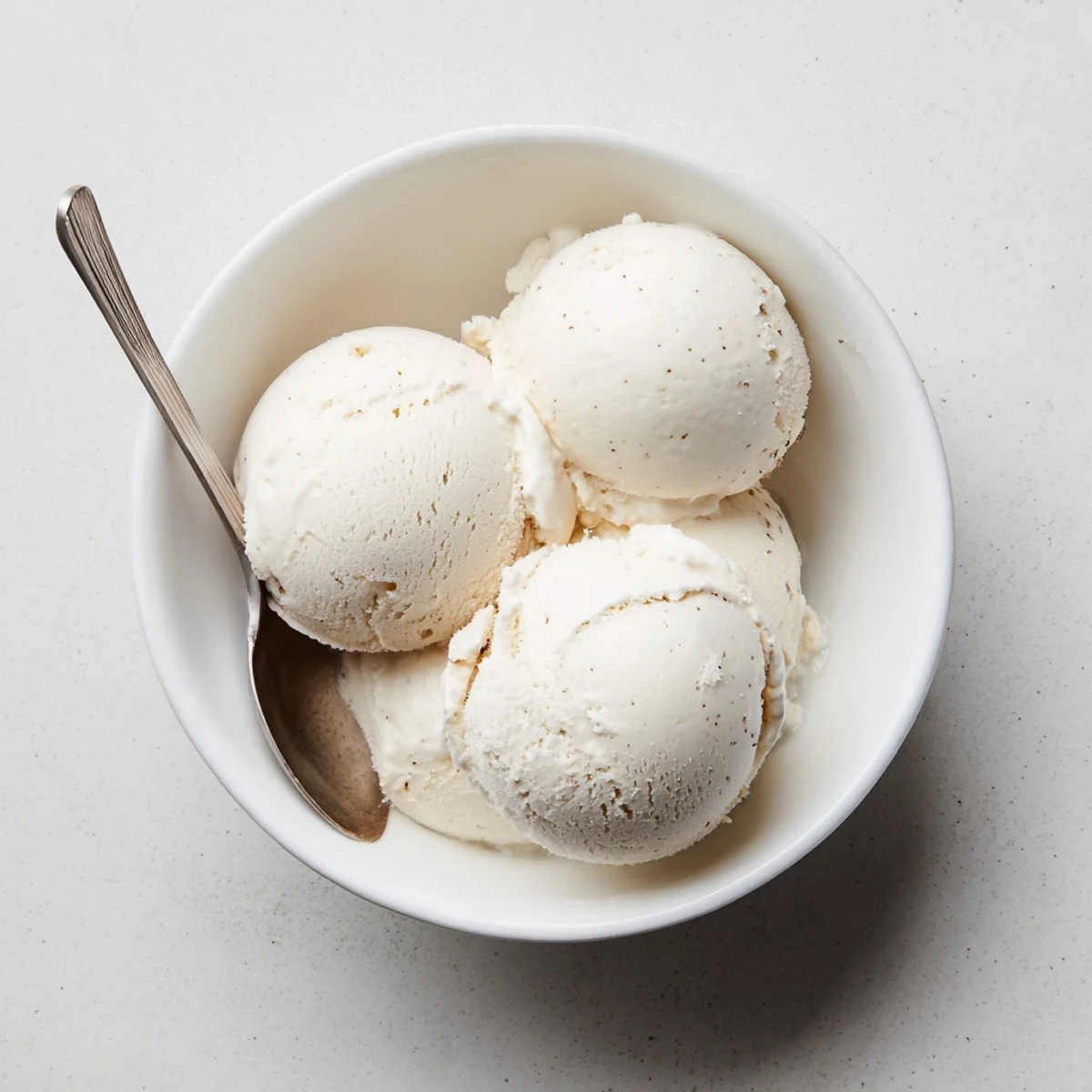 Rich custard-based vanilla ice cream swirl topped with fresh wafer cookie on a marble background