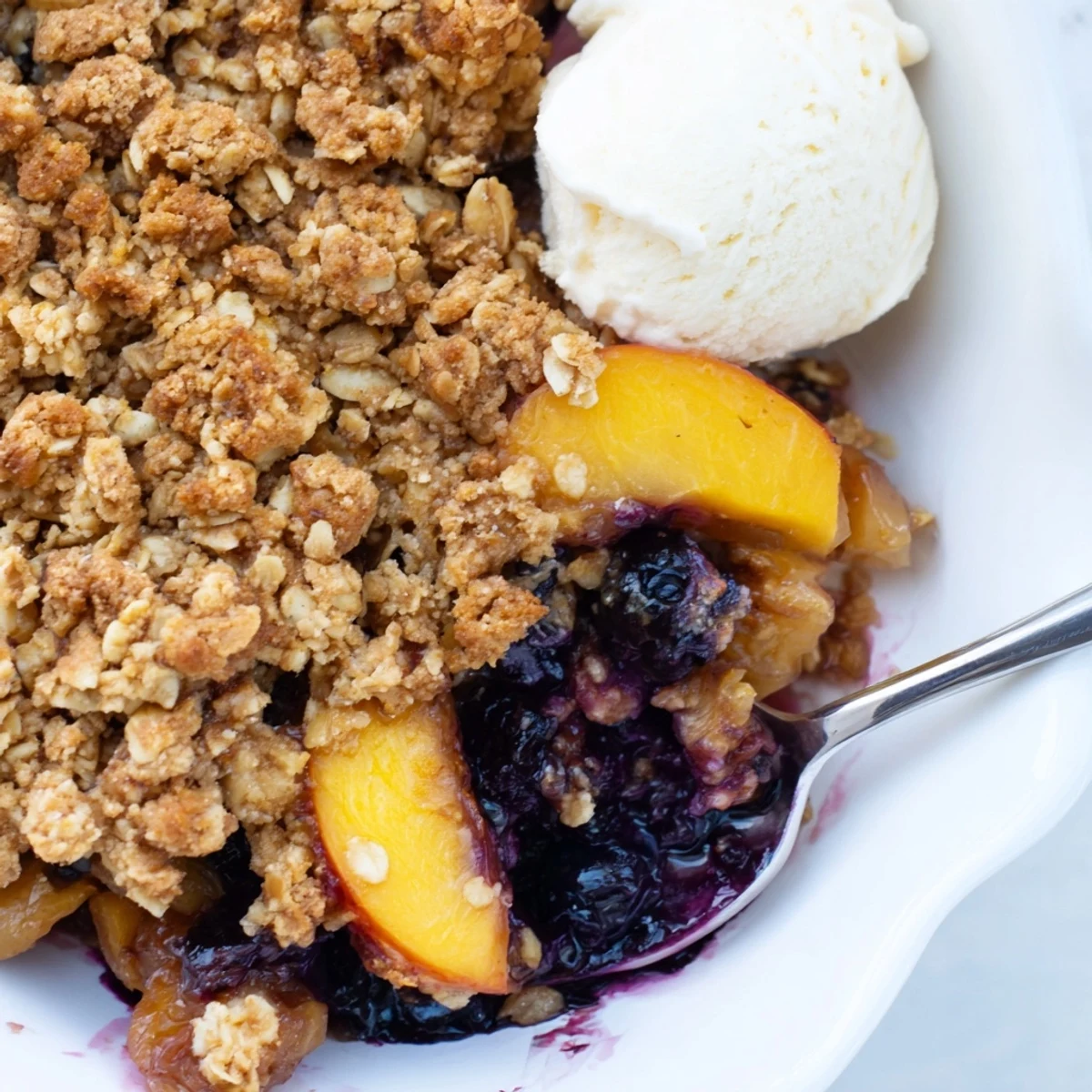 Blueberry Peach Crumble browned to golden, steam wafting, spoon resting nearby