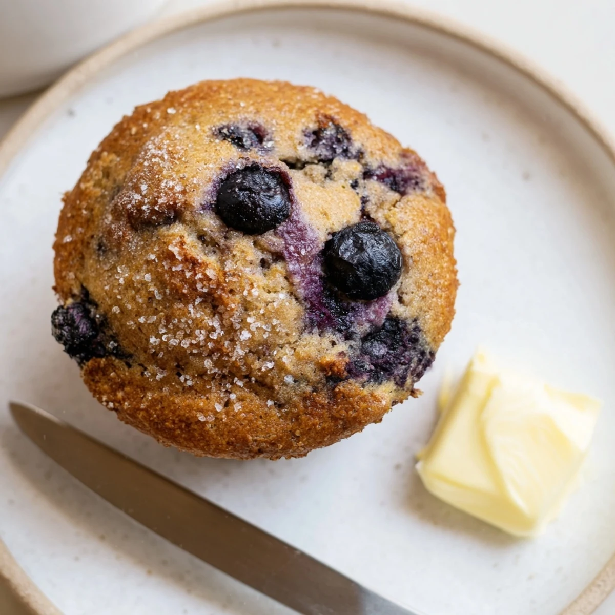 Blueberry Banana Muffins steaming on a wire rack, golden tops and blueberries.