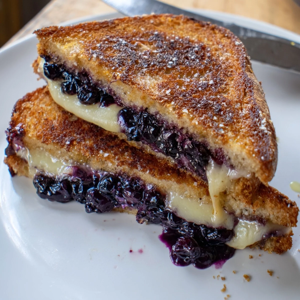 Pan-seared Crispy Blueberry Grilled Cheese sliced, steaming, served with lemony honey drizzle