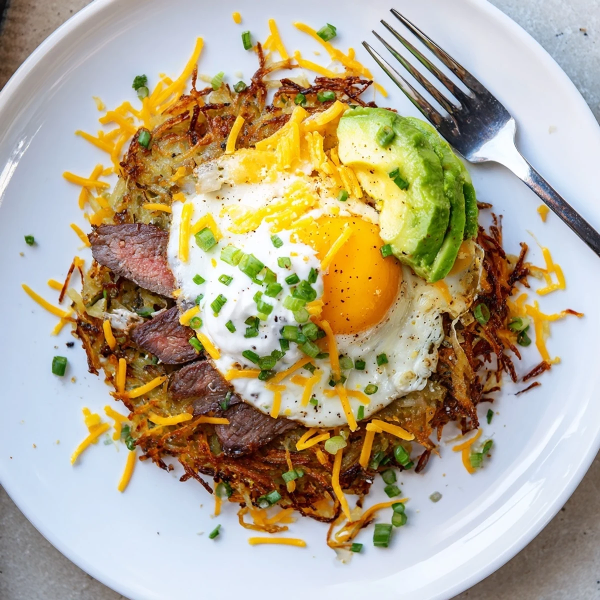 Loaded Steak Egg Hash Brown Stacks Recipe featuring seared steak, melted cheddar, runny egg
