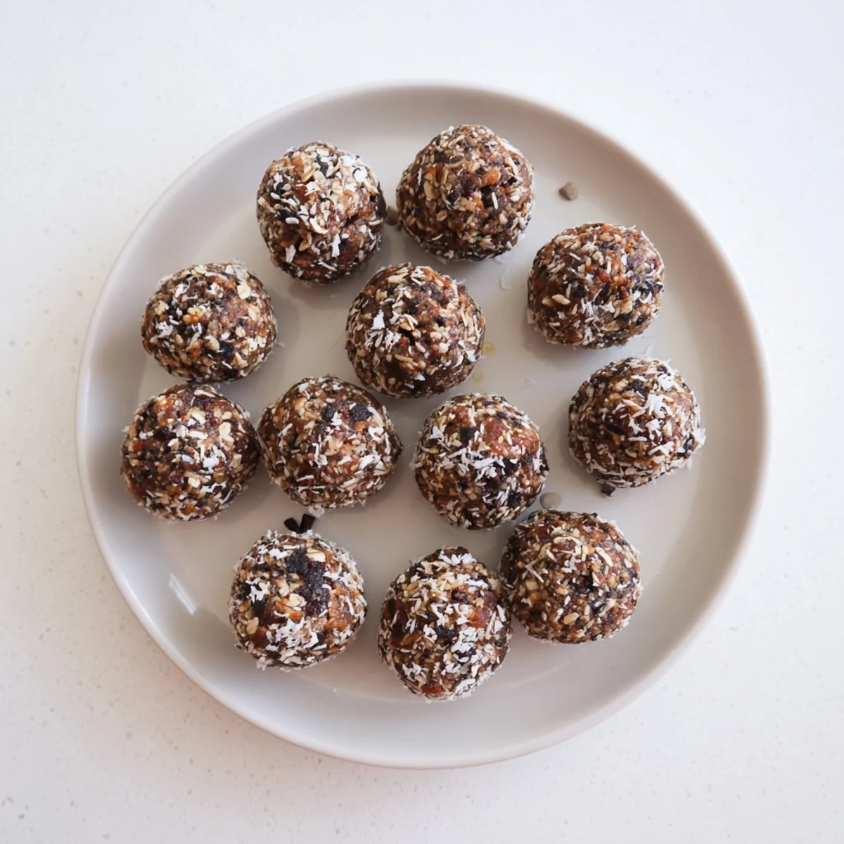 Homemade date energy balls rolled in coconut on a white serving plate