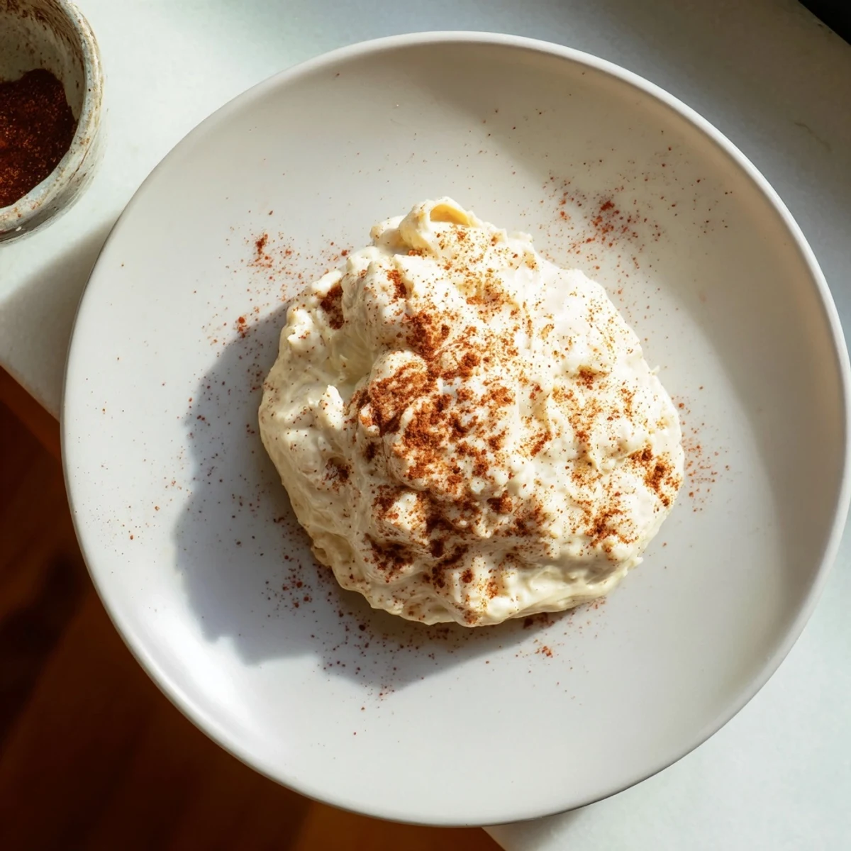 Creamy smoky garlic sauce in a white bowl with roasted garlic cloves and drizzled olive oil