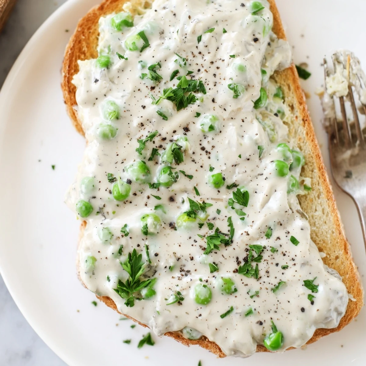 Buttery toast piled high with tender green peas in rich white cream sauce