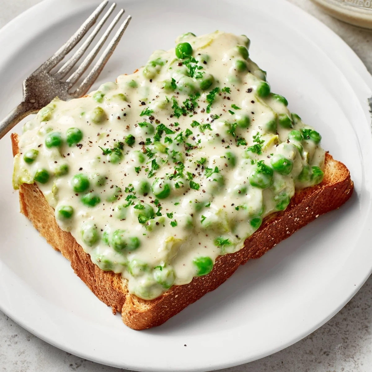 Comforting creamed peas on toast served on white plate with wooden spoon