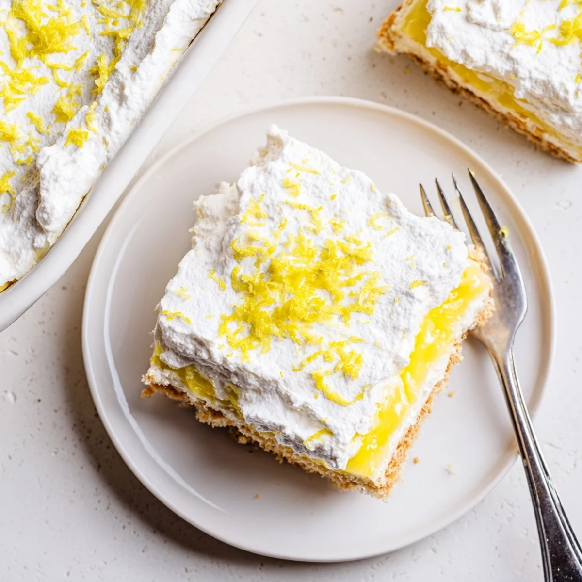 Golden slice of Lemon Lush Cake showcasing fluffy cream cheese and bright lemon pudding layers