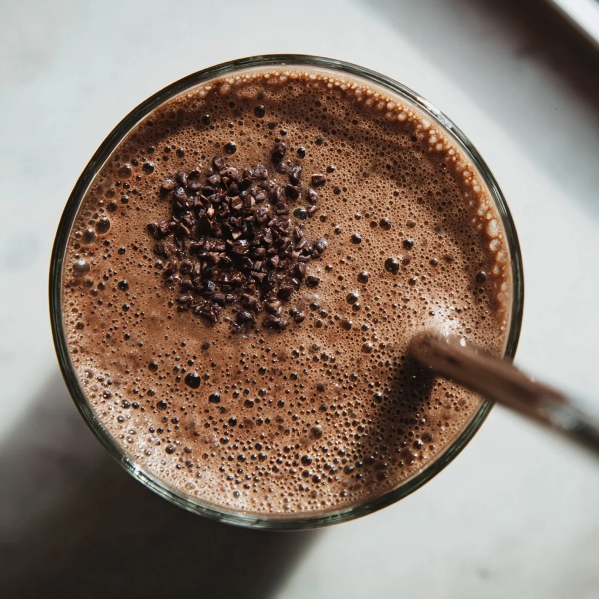 Creamy vegan raw chocolate banana shake blending frozen bananas and rich cacao powder