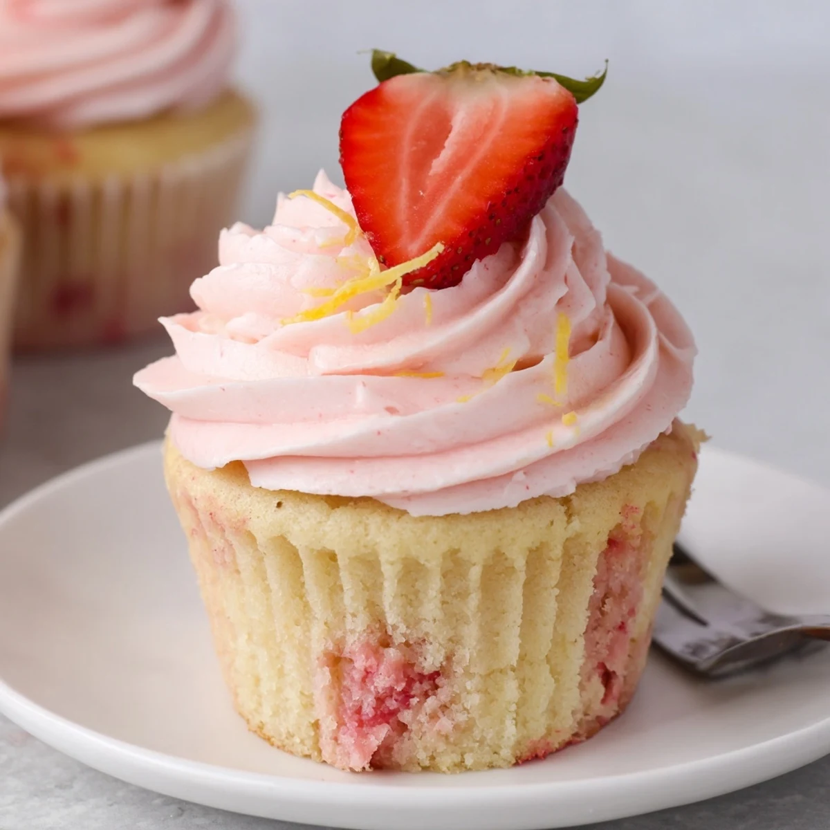 Strawberry Lemonade Cupcakes topped with swirled pink buttercream and a sliced strawberry