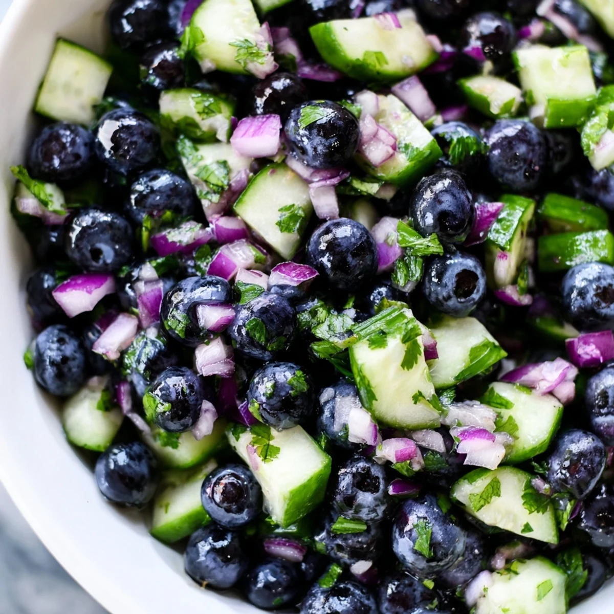 Blueberry cucumber salsa topped with cilantro and lime zest, served chilled in a clear dish