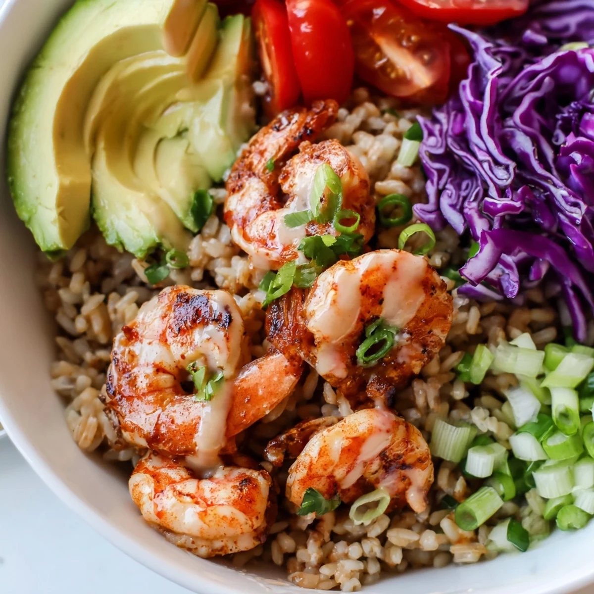 Shrimp grain bowl topped with sliced avocado cherry tomatoes and zesty lime dressing