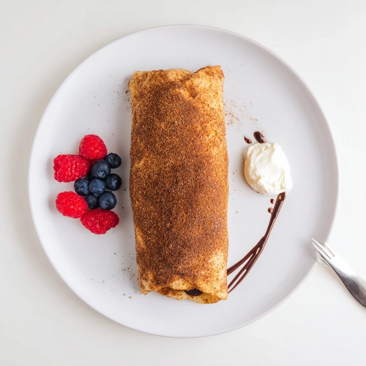 Golden cinnamon sugar cheesecake chimichangas served with fresh berries and chocolate drizzle