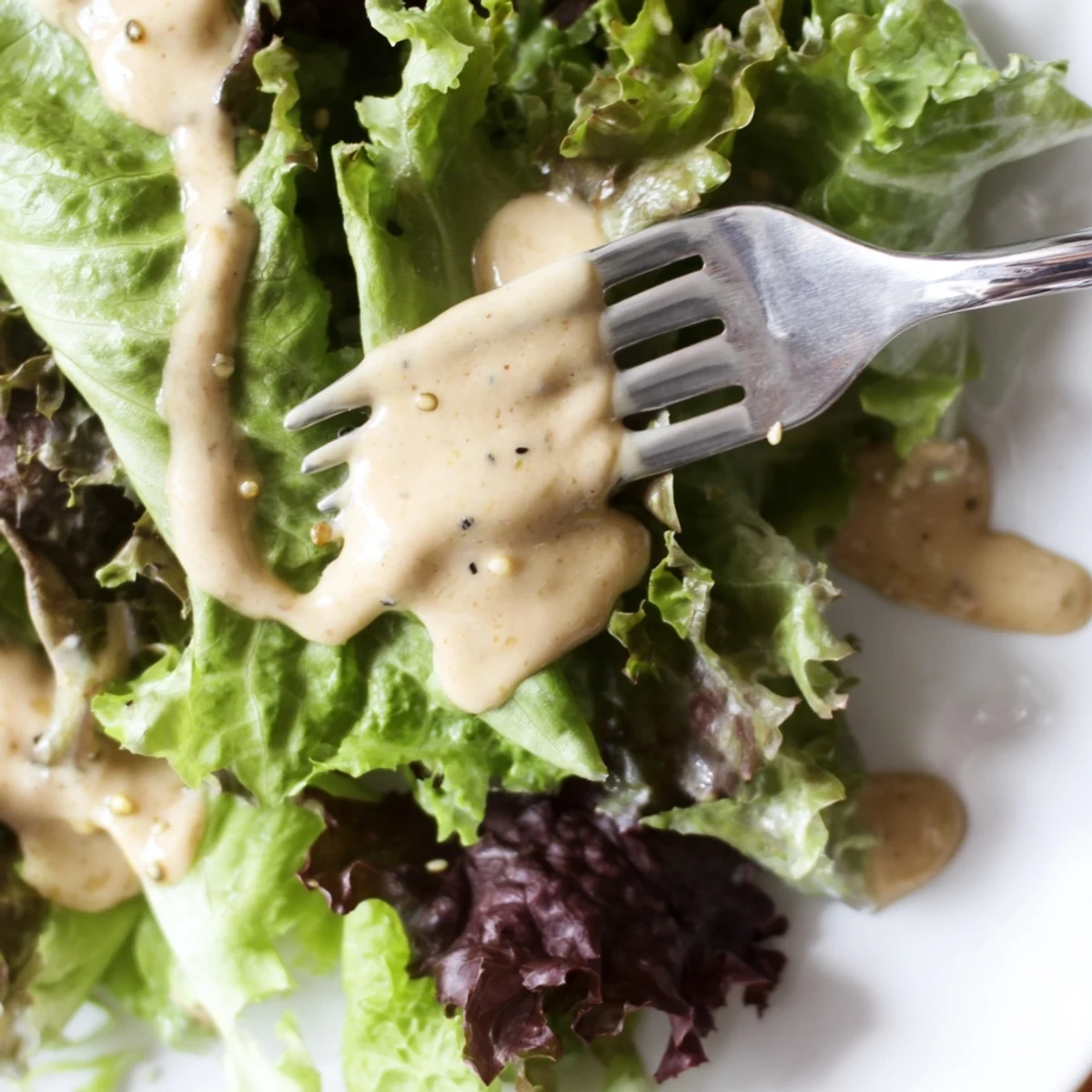 Smooth Asian-inspired dressing with nutty aroma poured from glass jar spoon