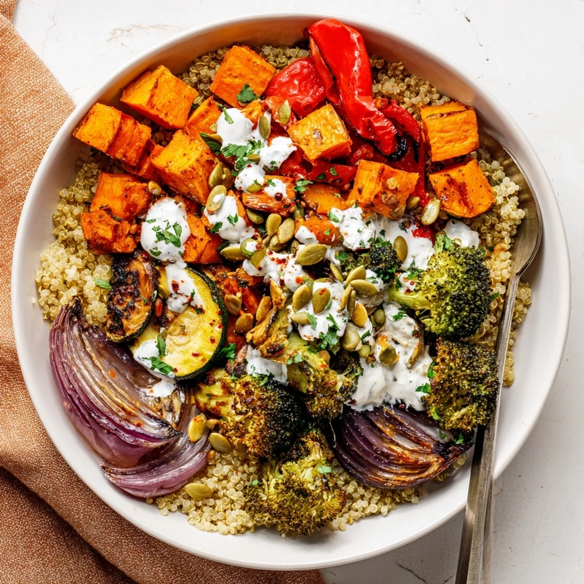 Grain bowl with roasted vegetables drizzled with creamy tahini dressing on rustic ceramic plate