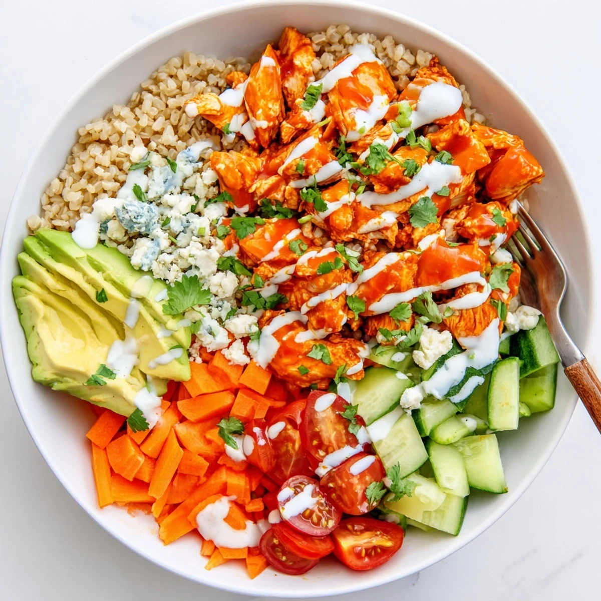A vibrant Buffalo Chicken Grain Bowl topped with crisp vegetables and creamy dressing
