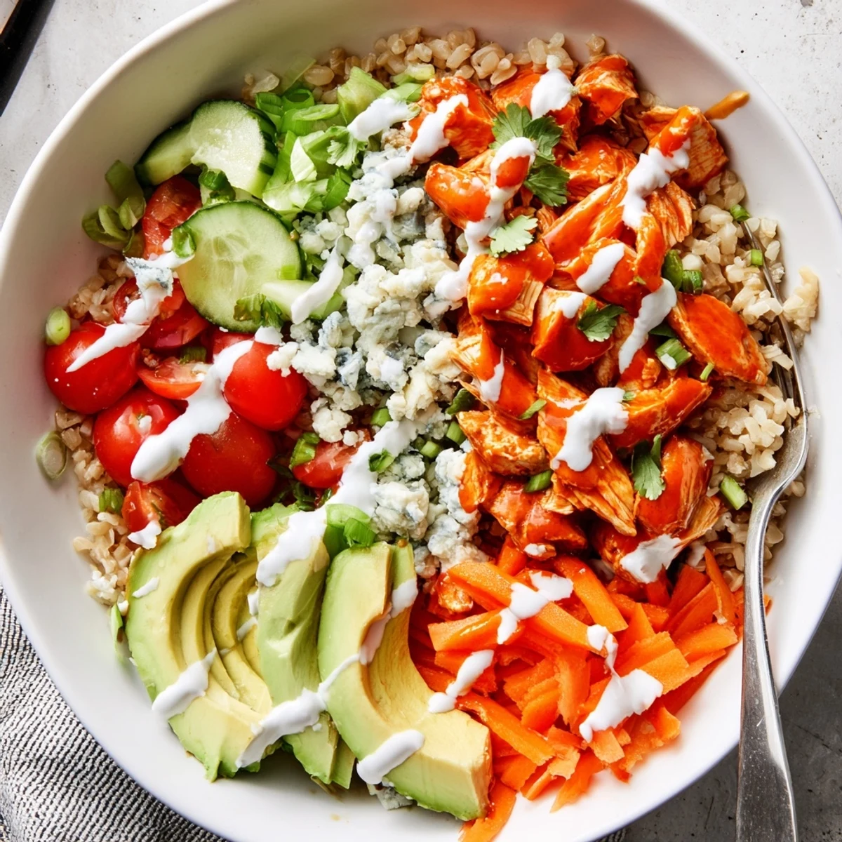 Hearty Buffalo Chicken Grain Bowl drizzled with tangy ranch and garnished with green onions
