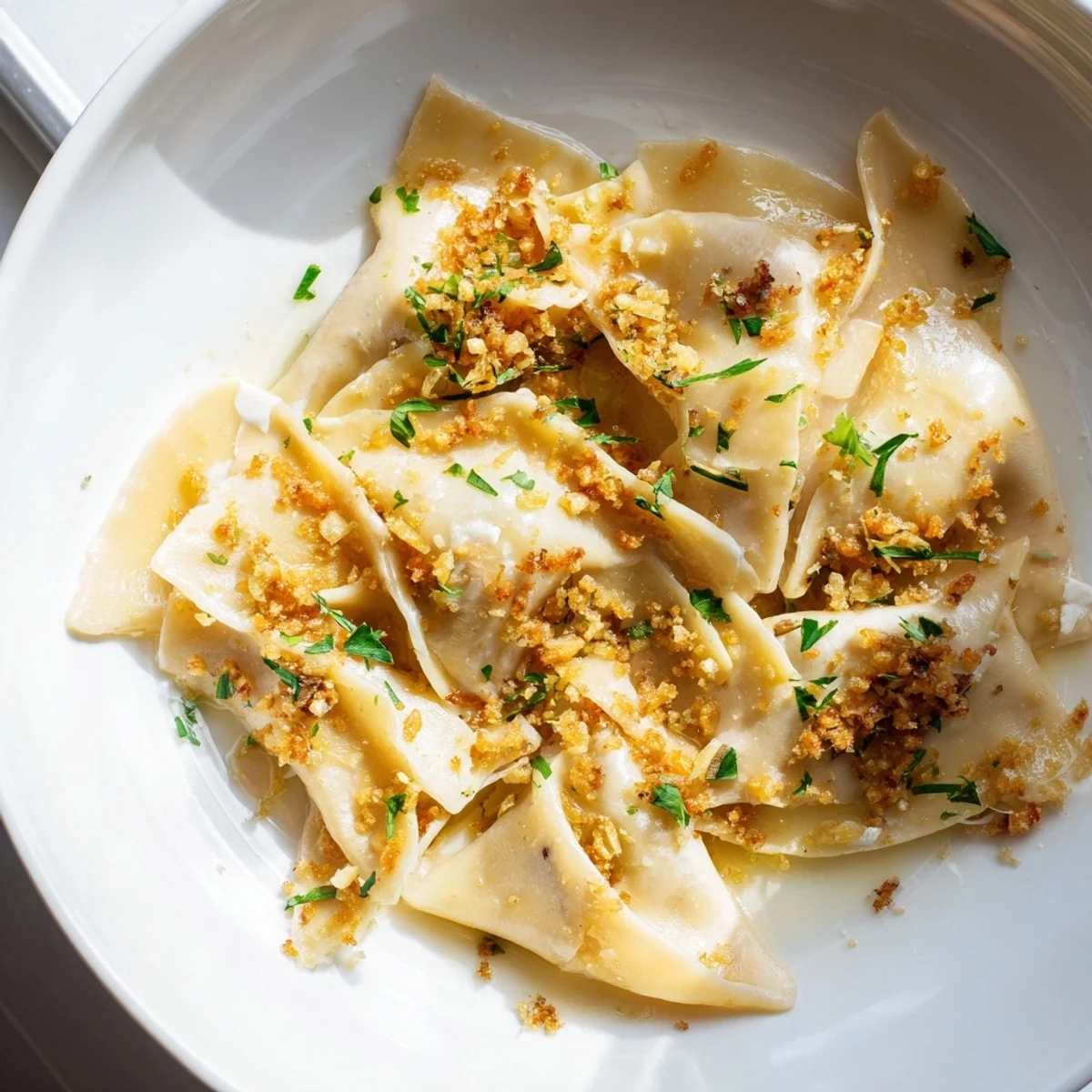 Creamy leek burrata triangoli plated on a white dish with herb-flecked golden topping
