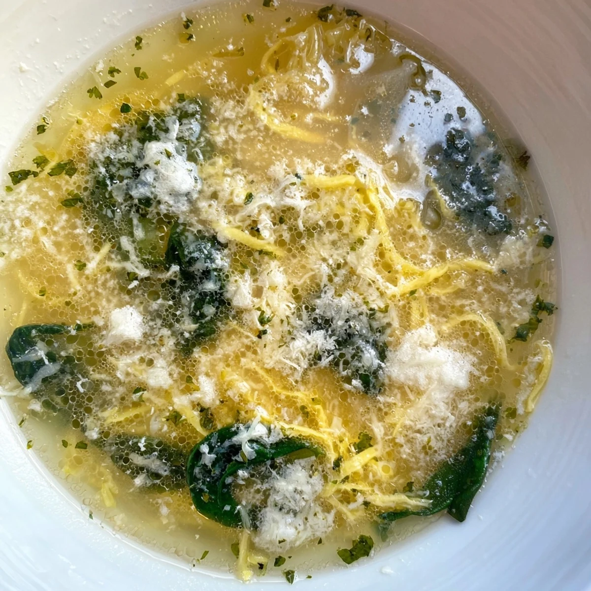Golden egg curds floating in a warm bowl of Italian Stracciatella Soup