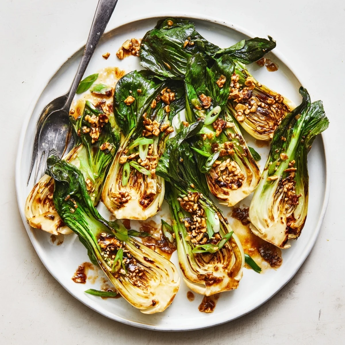 Golden caramelized garlic bok choy glistening in savory soy sesame glaze on a plate