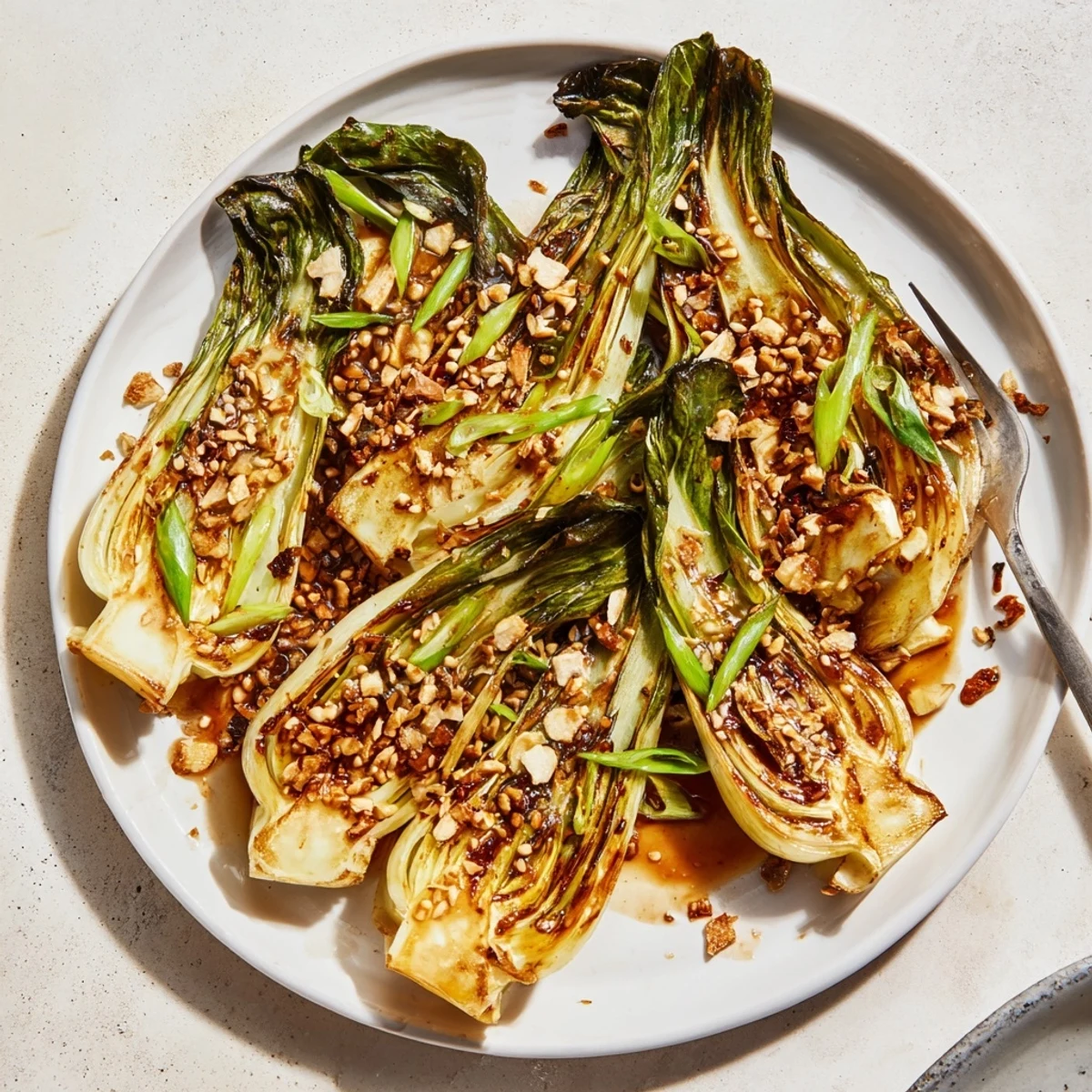 Crispy seared caramelized garlic bok choy topped with sesame seeds and green onions