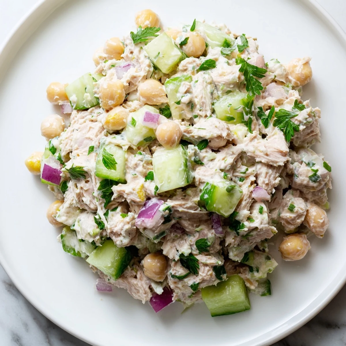 Hearty creamy tuna chickpea cucumber salad scooped into a toasted pita half