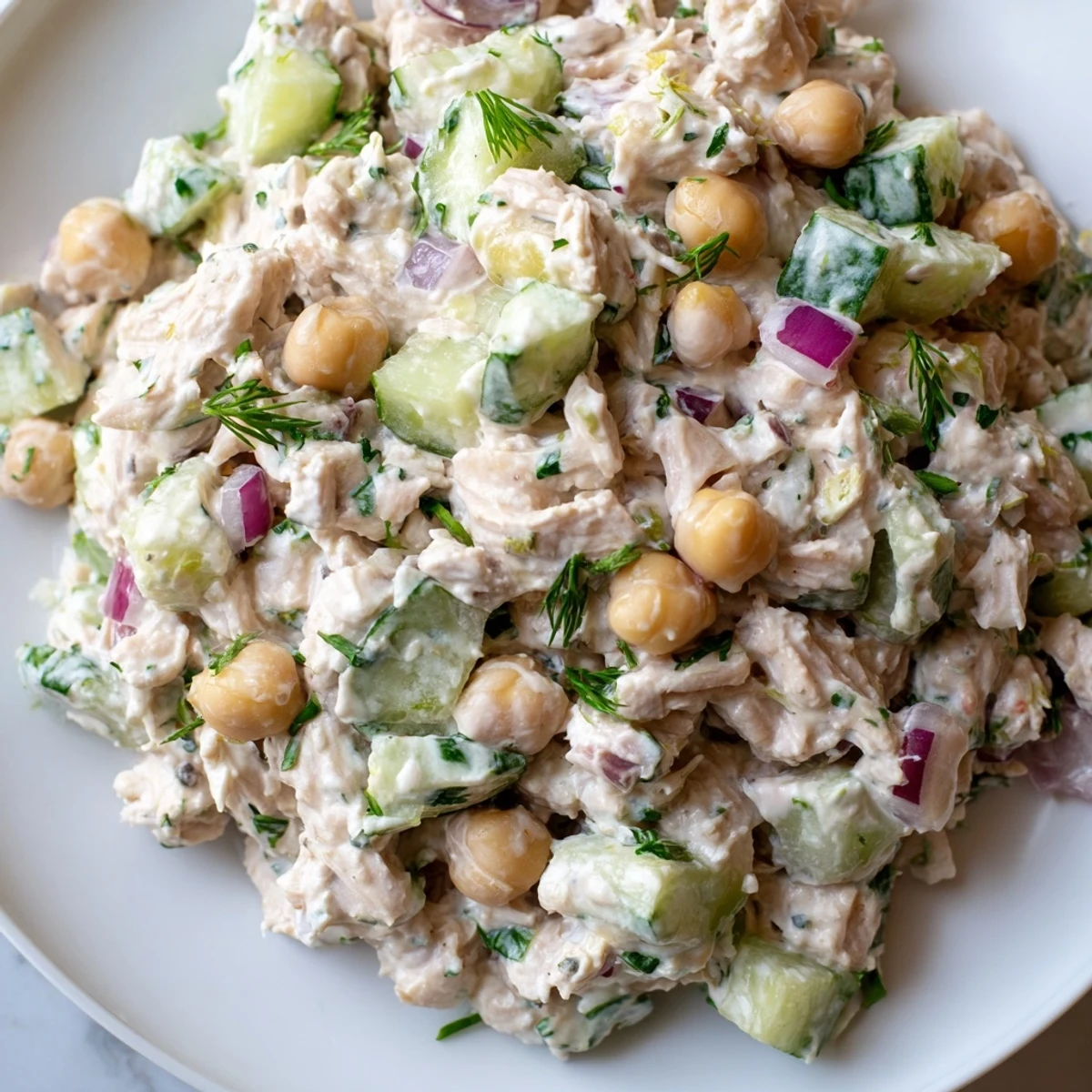 Tuna chickpea cucumber salad with creamy dressing piled on crisp lettuce leaves
